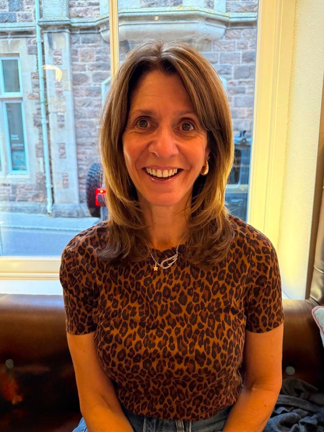 Vicky smiling, seated by a window